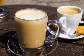 Close up outdoors of isolated brown dutch milk coffee (koffie verkeerd) in transparent glass mug...