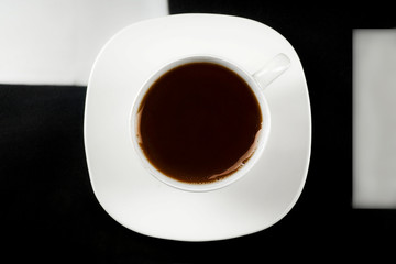 Cup of coffee on a black background - top view