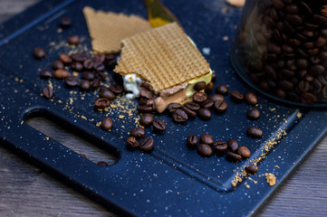 Cut of vanilla, chocolate and cream ice cream next to waffles and coffee beans.