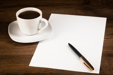 Obraz na płótnie Canvas A cup of coffee, a large piece of paper with a pen on the counter from the desk