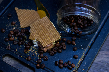 Cut of vanilla, chocolate and cream ice cream next to waffles and coffee beans.