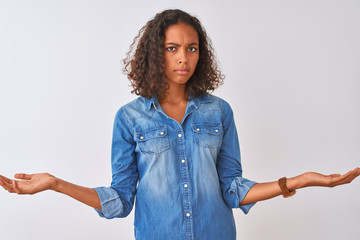Young brazilian woman wearing denim shirt standing over isolated white background clueless and...