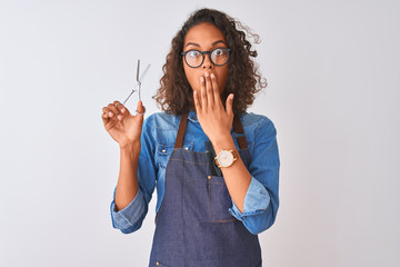 Young brazilian hairdresser woman using scissors standing over isolated white background cover mouth with hand shocked with shame for mistake, expression of fear, scared in silence, secret concept