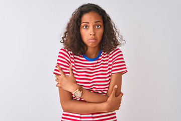 Young brazilian woman wearing red striped t-shirt standing over isolated white background shaking and freezing for winter cold with sad and shock expression on face