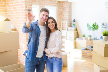 Fototapeta na wymiar Beautiful young couple hugging in love and showing keys of new house, smiling happy moving to a new apartment