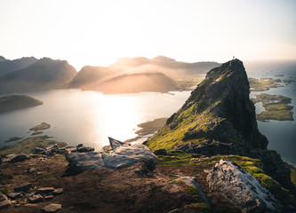 Volandstinden mountain at sunset. person standing on the mountain watching the sunset