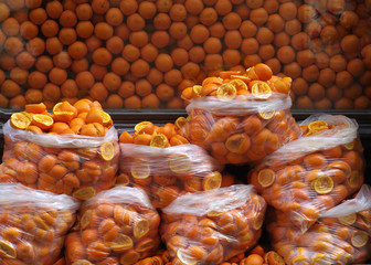 Peel squeezed for the juice of oranges in plastic bags on the background of a large number of fresh oranges.
