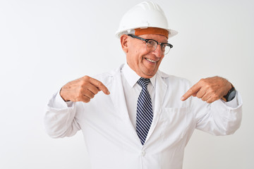 Senior grey-haired engineer man wearing coat and helmet over isolated white background looking...