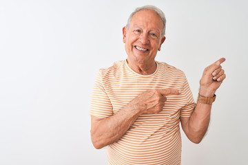 Senior grey-haired man wearing striped t-shirt standing over isolated white background smiling and looking at the camera pointing with two hands and fingers to the side.