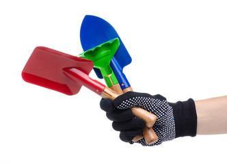 Hands in working gloves holding gardening tools rake shovel on white background isolation