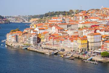 Fototapeta premium Rzeka Douro z nabrzeżem Porto i łodziami. Panoramiczny punkt orientacyjny Porto w słoneczny dzień. Stare budynki z ceglanymi dachami nad rzeką Douro w Porto, Portugalia. Historyczna dzielnica Porto. Portugalskie wakacje