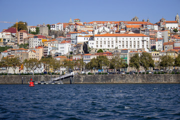 River Douro with colorful embankment of Porto. Porto panoramic landmark with boats on sunny day. Old buildings with brick roofs by river Douro in Porto, Portugal. Historic district of Porto. 
