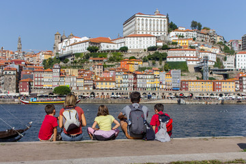 Porto, Portugal - 10/22/2019: Family back view sitting on embankment of river Douro, Porto,...