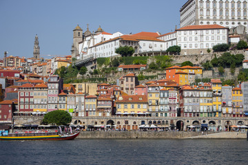 River Douro with colorful embankment of Porto. Porto panoramic landmark with boats on sunny day. Old buildings with brick roofs by river Douro in Porto, Portugal. Historic district of Porto. 