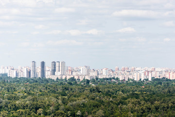 Urban scene with trees in city park, skyscrapers and buildings
