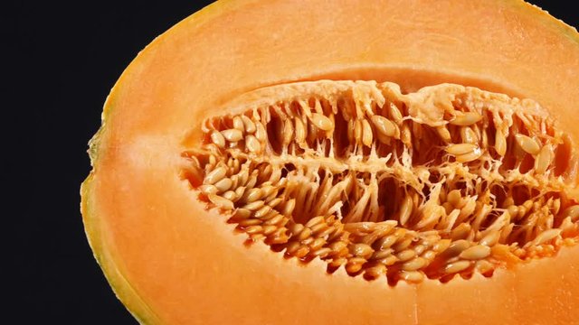Half cantaloupe melon isolated on the black background, 4K tracking shot