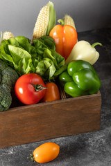 Fresh vegetables in a wooden box on a dark wooden background.