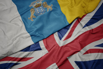 waving colorful flag of great britain and national flag of canary islands.