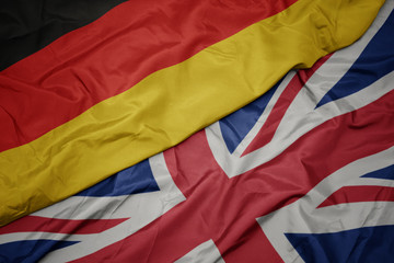 waving colorful flag of great britain and national flag of germany.