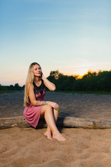 Fototapeta na wymiar Portrait of the beautiful blond model with long hair on the sand beach