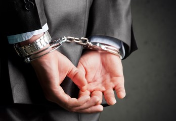 Cropped image of male hands in handcuffs behind his back