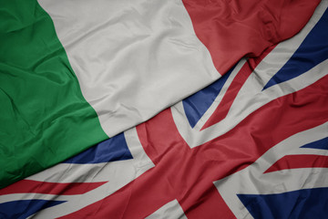 waving colorful flag of great britain and national flag of italy.
