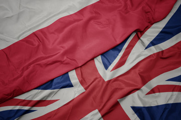 waving colorful flag of great britain and national flag of poland.