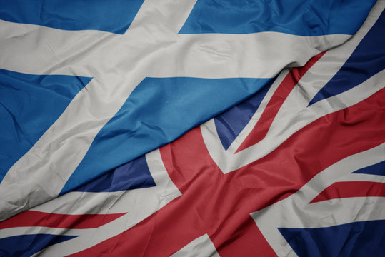 waving colorful flag of great britain and national flag of scotland.