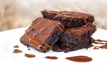 Homemade brownie served with chocolate fudge. Sweet dessert on wooden background.