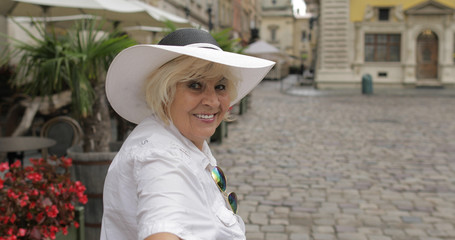 Senior female tourist makes someone to follow her through the city Lviv, Ukraine