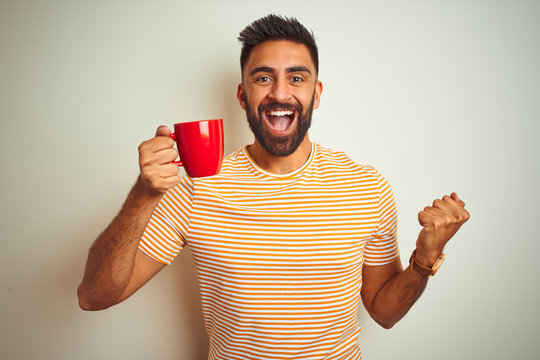 Young Indian Man Drinking Red Cup Of Coffee Standing Over Isolated White Background Screaming Proud And Celebrating Victory And Success Very Excited, Cheering Emotion