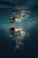 Girl in a dress with ribbons swims underwater
