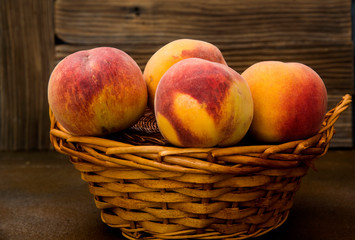 Peaches in a wicker basket on rustic background