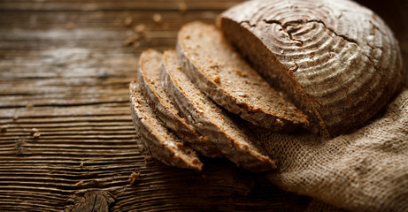 Bread,  traditional spelled sourdough bread cut into slices on a rustic wooden background,...