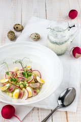 Okroshka on kefir with tuna, radish, quail eggs on wooden white table. Cold summer soup in many countries