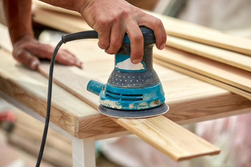 Grinder worker polishes a wooden board. Sanding boards Orbital eccentric machine.