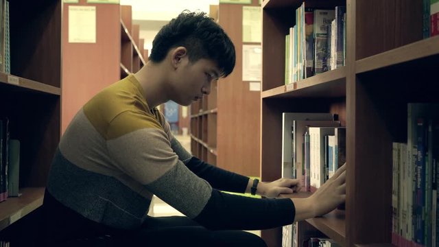 Asian student reads book in the library, lessons for exams, educational concepts