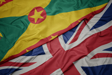 waving colorful flag of great britain and national flag of grenada.