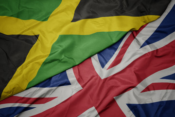 waving colorful flag of great britain and national flag of jamaica.