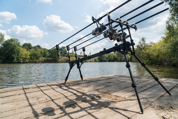 Carp fishing, rodpod with fishing rods on a wooden platform on the lake