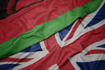 waving colorful flag of great britain and national flag of malawi.