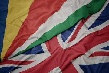 waving colorful flag of great britain and national flag of seychelles.