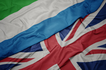 waving colorful flag of great britain and national flag of sierra leone.