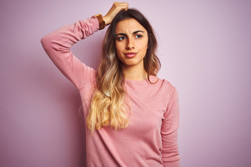 Young beautiful woman wearing a sweater over pink isolated background confuse and wonder about question. Uncertain with doubt, thinking with hand on head. Pensive concept.