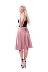 Back view of young blonde stylish woman in skirt walking away turning and waving hand goodbye to camera. Full body isolated on white background. 
