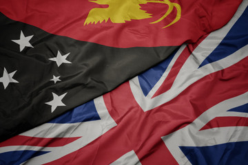 waving colorful flag of great britain and national flag of Papua New Guinea.