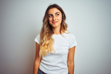 Young beautiful woman wearing casual white t-shirt over isolated background smiling looking to the...