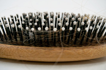 hairbrush with a wooden handle for the head with hair on a white background