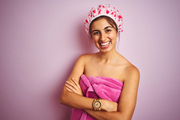 Obraz na płótnie Canvas Young beautiful woman wearing a shower towel after bath over pink isolated background happy face smiling with crossed arms looking at the camera. Positive person.