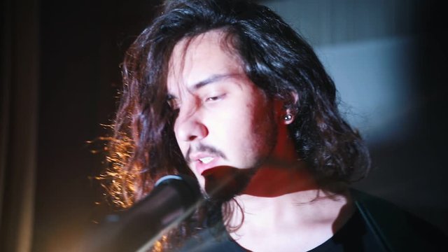 A young man with long hair walking to the mic on the stage and starts talking
